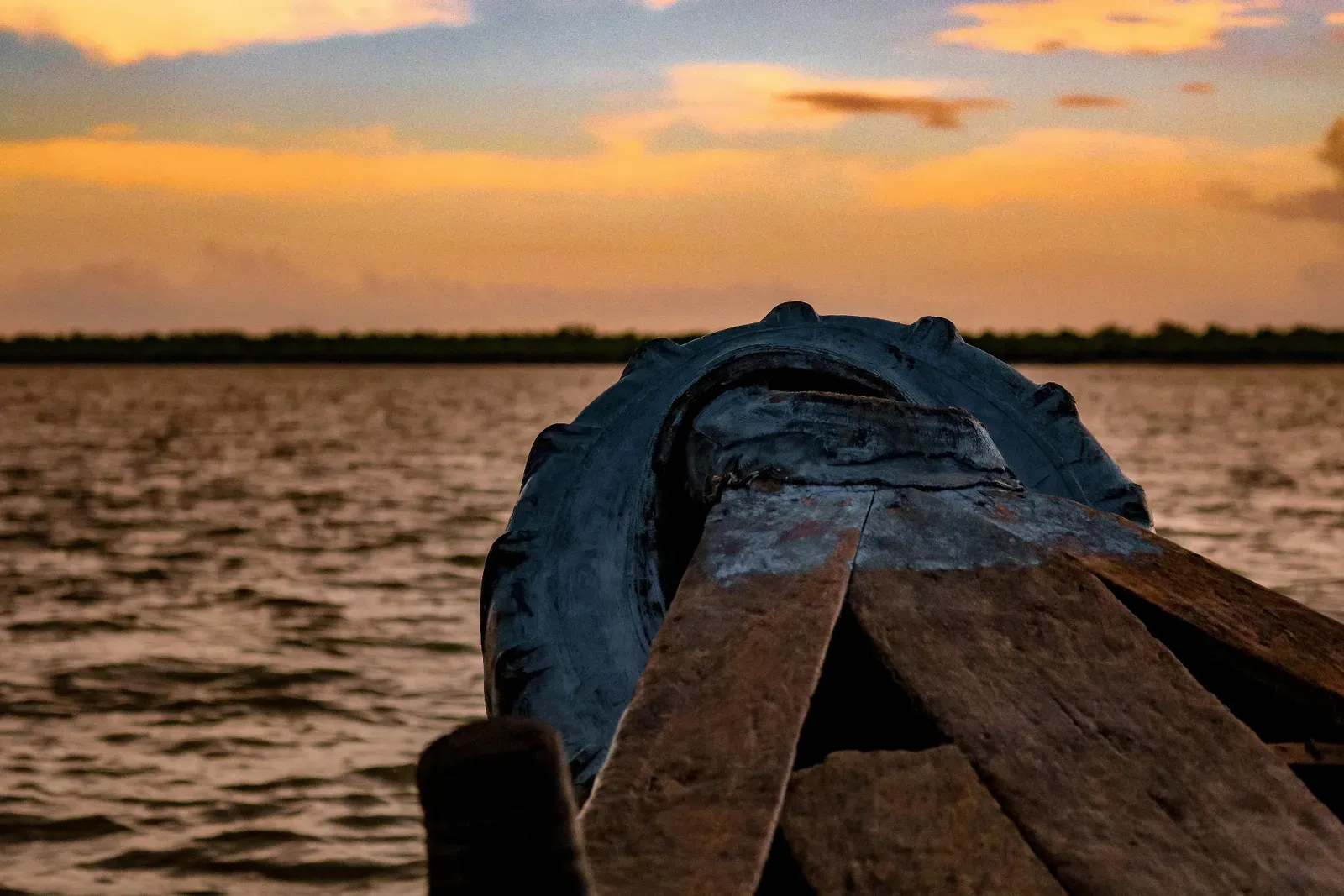 Traditional wooden boat sailing at sunset on Sundarban river
