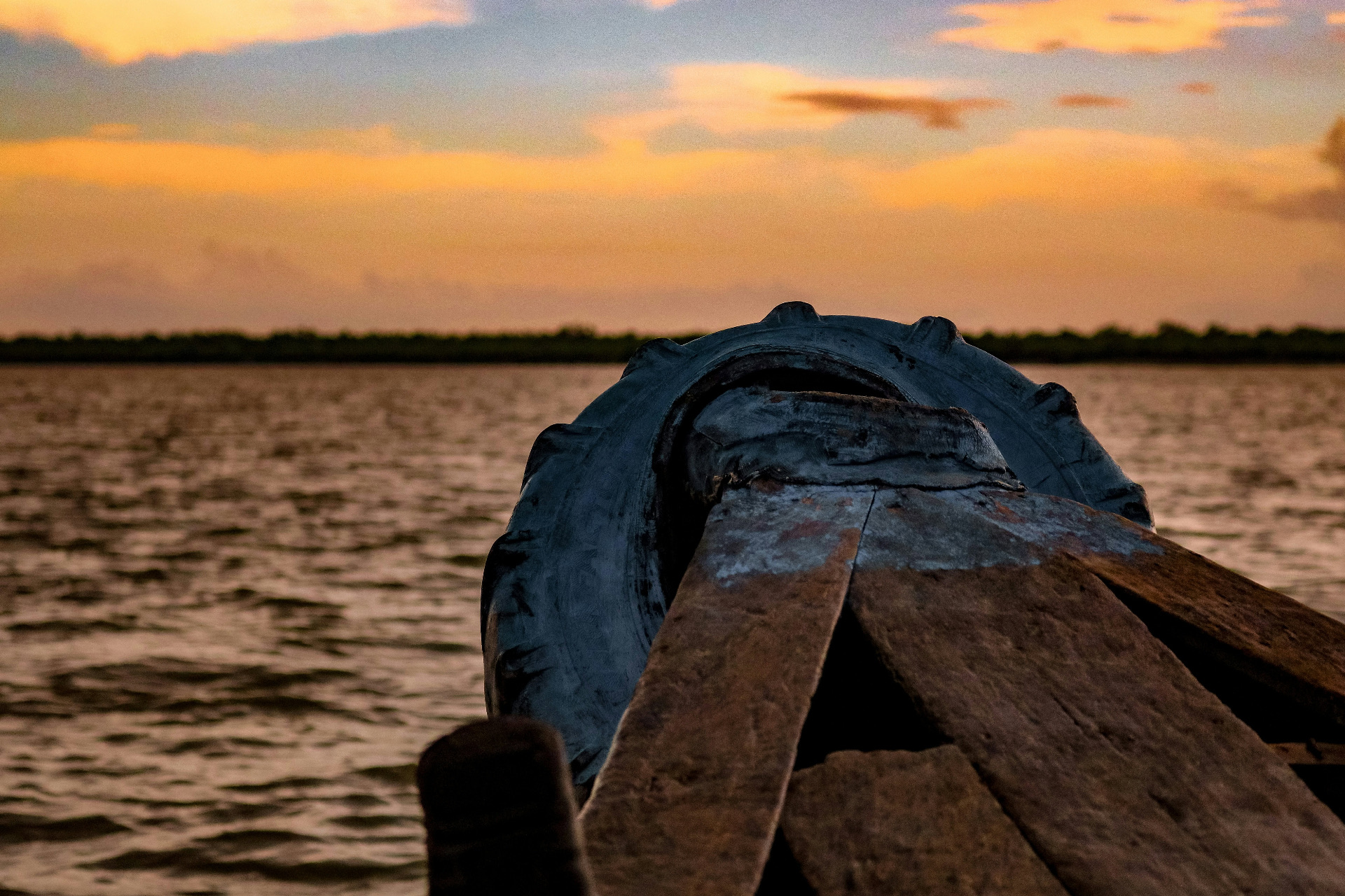 Traditional wooden boat sailing at sunset on Sundarban river